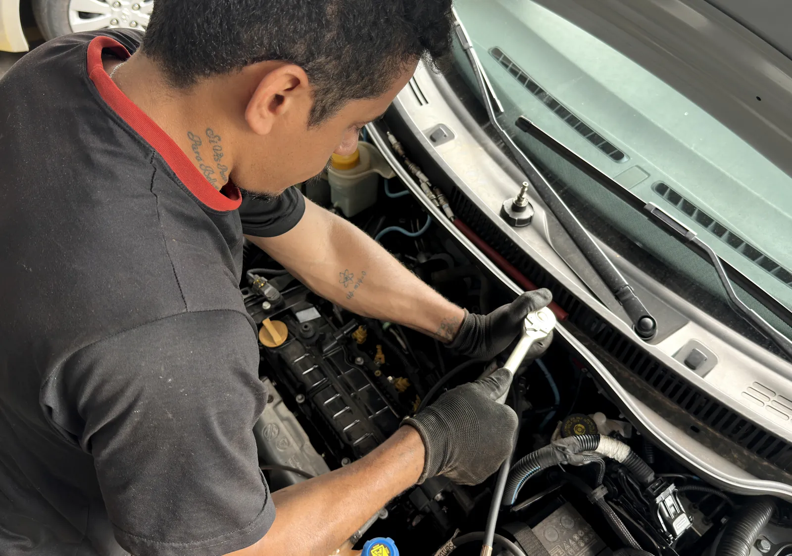 Mecânico com luvas trabalhando no motor com uma catraca