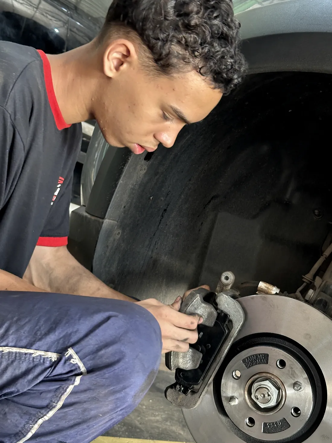 Mecânico encaixando pastilha de freio nova na pinça, ao lado do disco